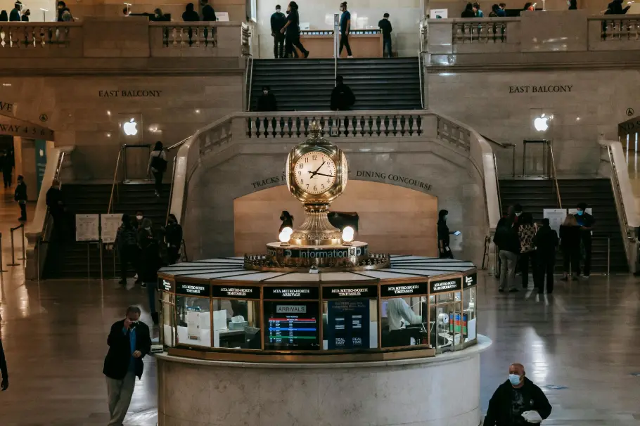 Un espace public historique avec l'horloge emblématique et le comptoir d'information du Grand Central Terminal, où des personnes marchent et montent les escaliers. Représente le rôle de la diffusion d'huiles essentielles dans la création d'une atmosphère apaisante et fraîche dans les espaces publics fréquentés.