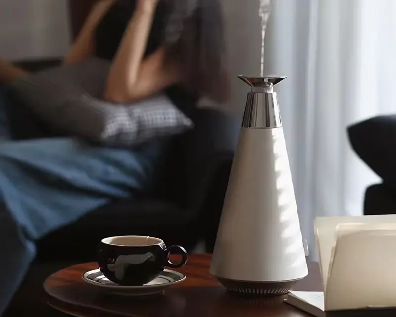 Sleek nebulizing diffuser on a table beside a coffee cup in a cozy home setting